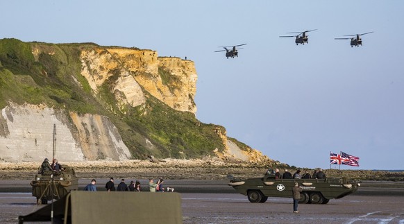 epa07629494 A handout picture provided by the British Ministry of Defence showing helicopters flying over amphibious vehicles on the beach at Arromanche, Normandy. France, 05 June 2019 issued 06 June  ...