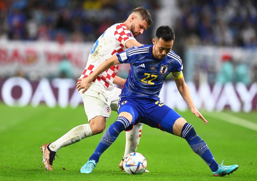 epa10349848 Maya Yoshida (R) of Japan in action against Bruno Petkovic (L) of Croatia during the FIFA World Cup 2022 round of 16 soccer match between Japan and Croatia at Al Janoub Stadium in Al Wakra ...