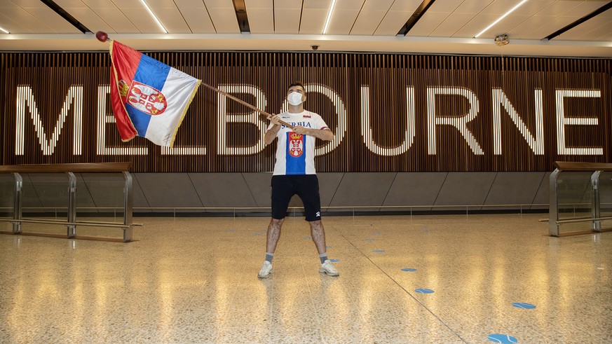 epa09668378 A fan of Serbian tennis player Novak Djokovic is seen waving a Serbian flag while awaiting the arrival of Novak Djokovic at Melbourne International Airport, in Melbourne, Australia, 06 Jan ...