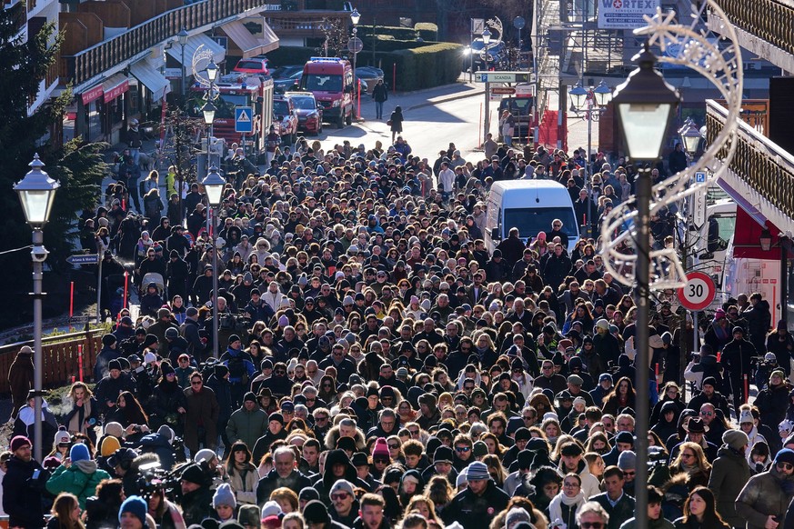 People walk during a memorial procession in Crans-Montana, Swiss Alps, Switzerland, Sunday, Jan. 4, 2026, after a devastating fire in Le Constellation bar left dead and injured during the New Year ...