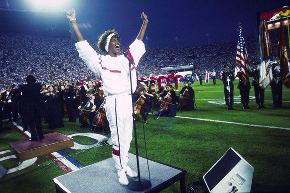 TAMPA, FL - JANUARY 27: Whitney Houston sings the National Anthem during the pregame show at Super Bowl XXV while tens of thousands of football fans wave tiny American flags in an incredible outburst ...