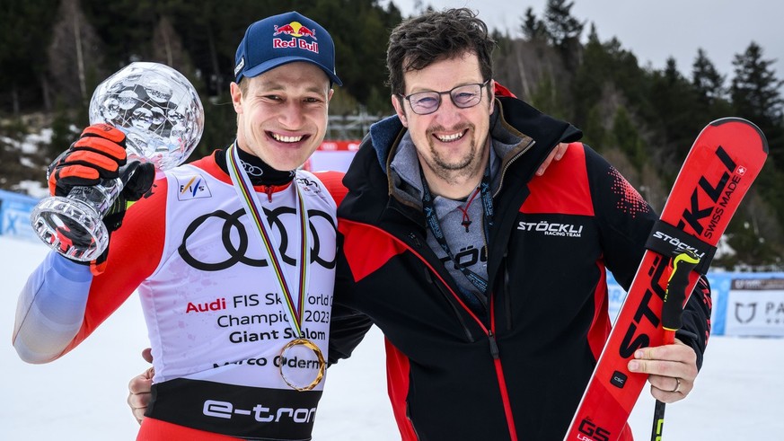 Marco Odermatt of Switzerland poses with the men&#039;s giant slalom overall leader crystal globe trophy next to serviceman Chris Loedler after the podium ceremony at the FIS Alpine Skiing World Cup f ...