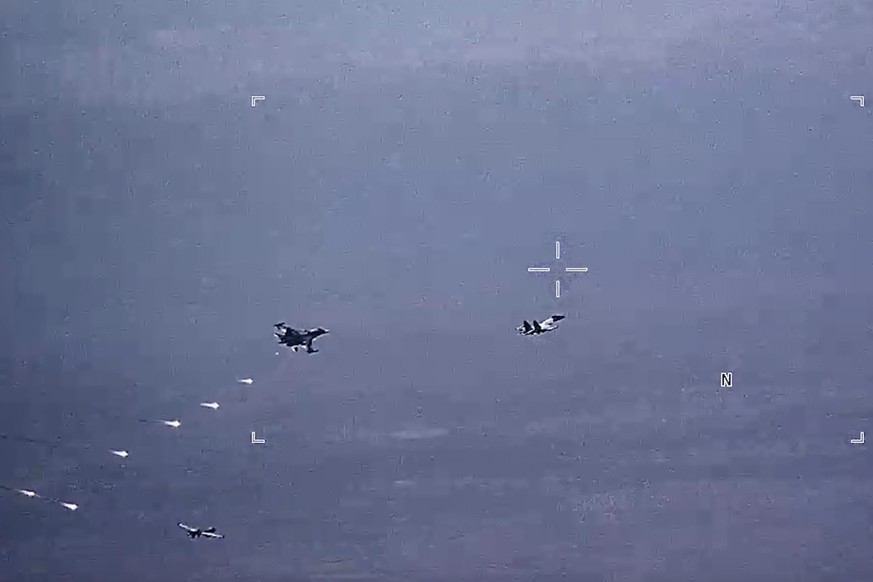 Des avions militaires russes lancent des fusées éclairantes sur un drone de l'armée de l'air américaine.
