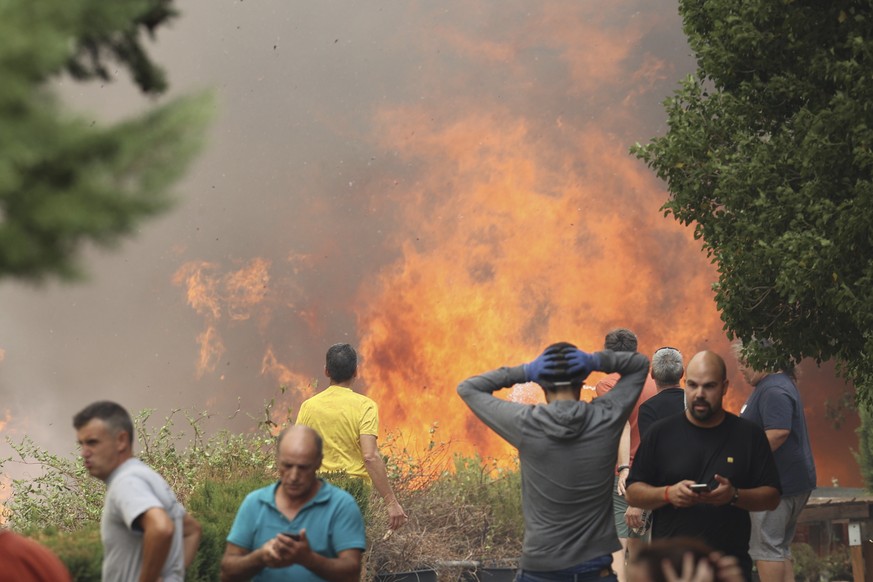 Neighbours stand near a forest fire in Anon de Moncayo, Spain on Saturday Aug. 13, 2022. A large wildfire in northeast Spain grew rapidly overnight and was burning out of control. It has already force ...