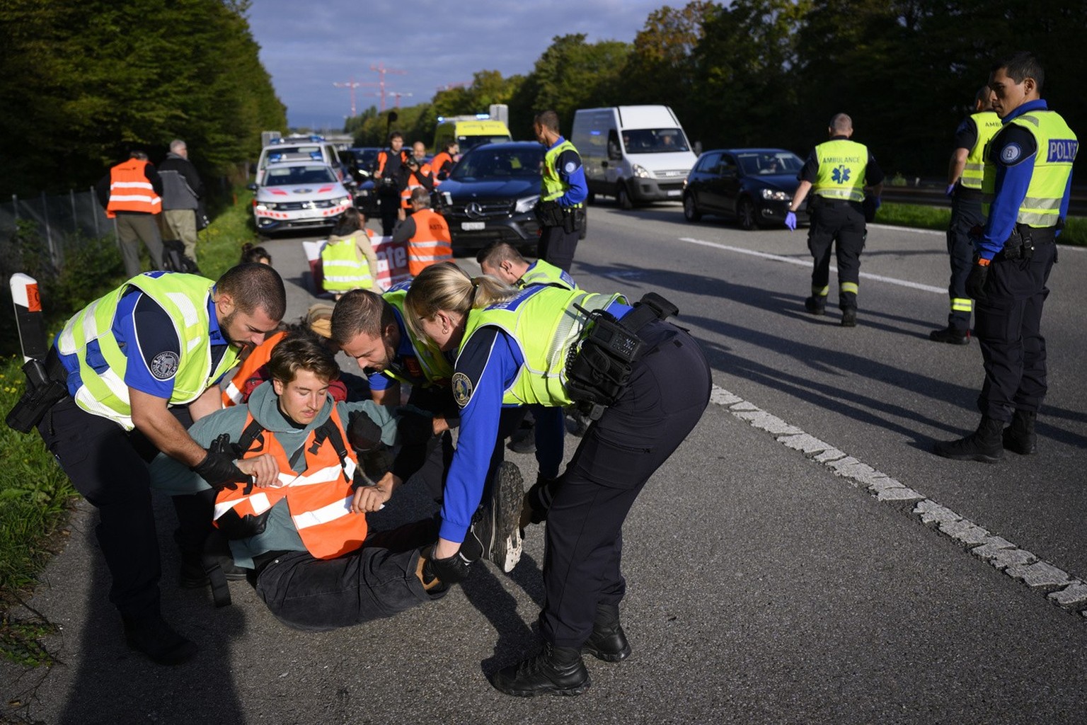 Police officers arrest environmental activist member of Renovate Switzerland after he sit down in the road during a roadblock action of the A1a motorway, in Lausanne, Switzerland, Tuesday, October 4,  ...