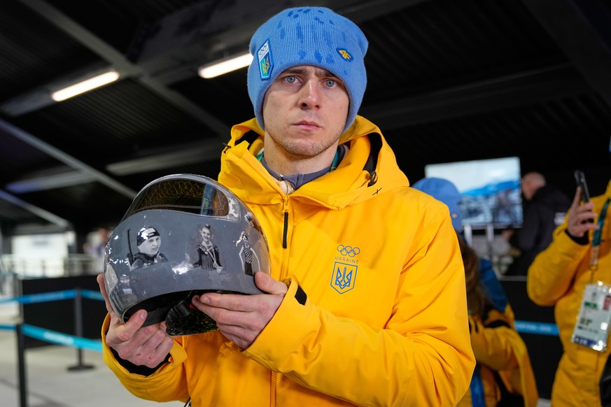 Ukrainian skeleton athlete Vladyslav Heraskevych holds his crash helmet as he stands in the mixed zone of the sliding center at the 2026 Winter Olympics, in Cortina d'Ampezzo, Italy, Thursday, Fe ...