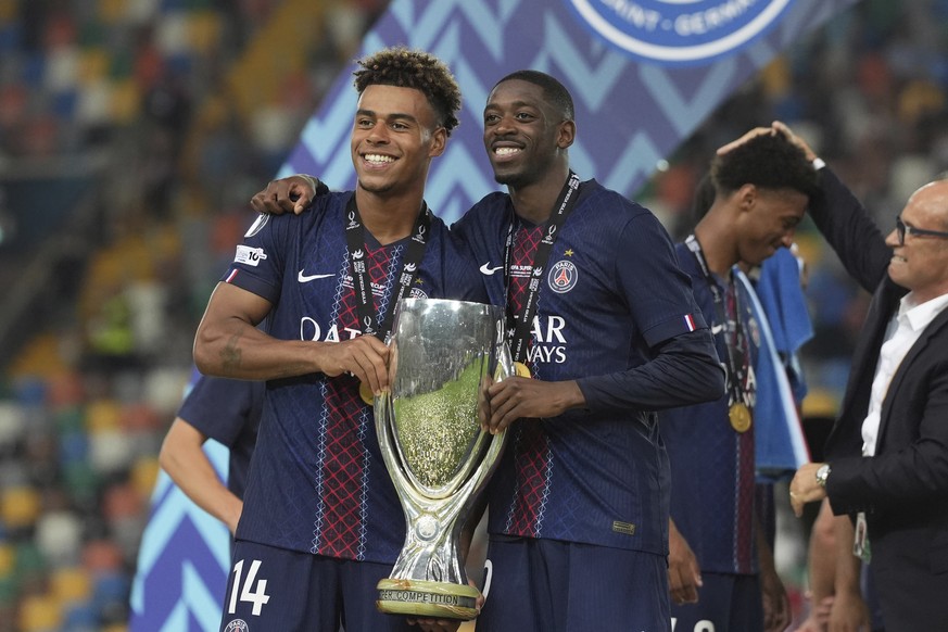 PSG&#039;s Desire Doue, left, Paris&#039;s Ousmane Dembele pose with the trophy after the UEFA Super Cup soccer match between Paris Saint-Germain and Tottenham Hotspur in Udine, Italy, Wednesday, Aug. ...