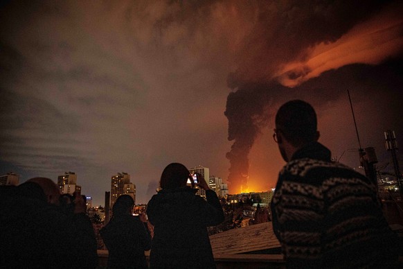 Residents look on and take pictures as flames and smoke rise from an oil storage facility struck as attacks hit the city during the U.S.Israeli military campaign in Tehran, Iran, Saturday, March 7, 2 ...
