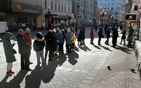 Des gens font la queue pour retirer de l'argent à un distributeur automatique à Moscou.