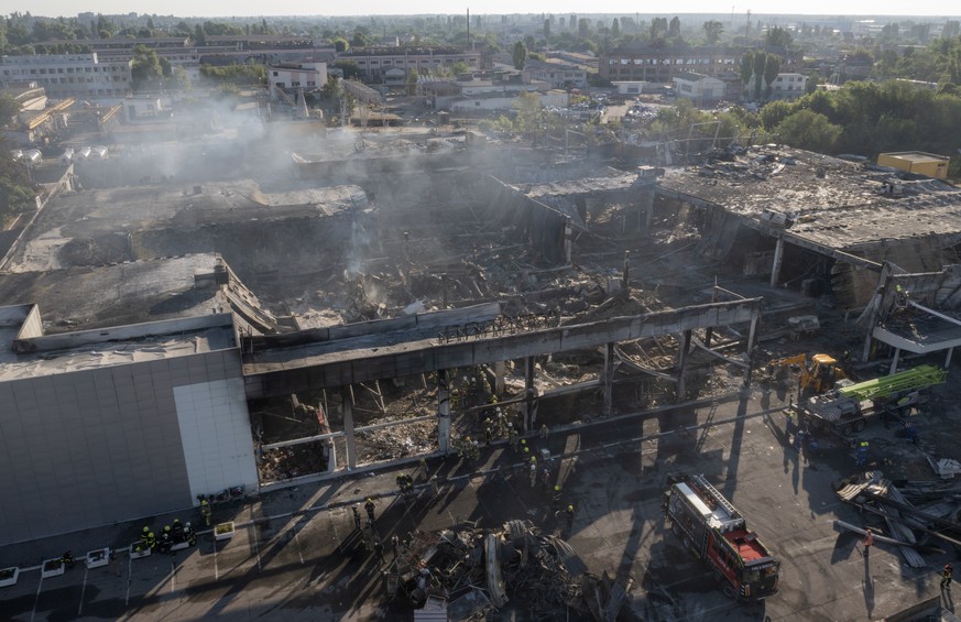 Ukrainian State Emergency Service firefighters work to take away debris at a shopping center burned after a rocket attack in Kremenchuk, Ukraine, Tuesday, June 28, 2022. (AP Photo/Efrem Lukatsky)