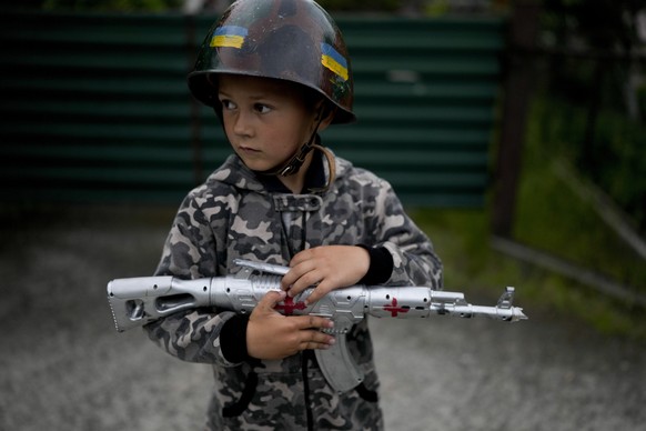 Valik Vladimirovich plays, dressed as a soldier, in Stoyanka on the outskirts of Kyiv, Ukraine, Monday, May 30, 2022. (AP Photo/Natacha Pisarenko)