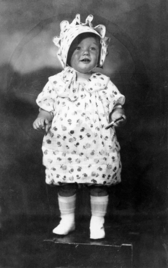 1928: Full-length studio portrait of American actor Marilyn Monroe (born Norma Jean Mortenson, 1926 - 1962) at the age of two, standing on a box in a floral print dress and matching bonnet. (Photo by  ...