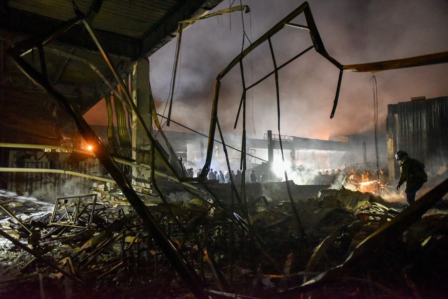 epa10037594 Firefighters clean the rubble of the destroyed Amstor shopping mall in Kremenchuk, Poltava Oblast, Ukraine, 27 June 2022. At least eleven bodies were found dead at the scene, the State Eme ...