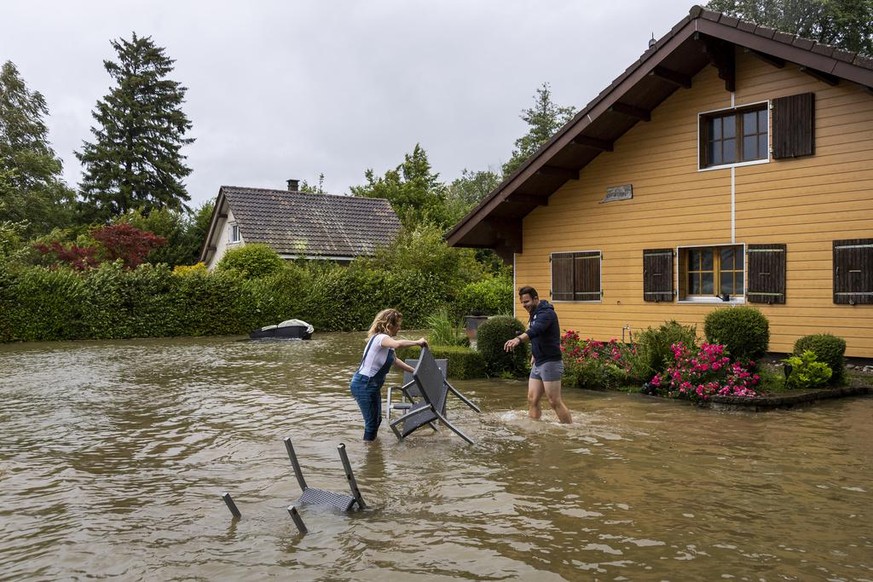 Deux residents enlevent du mobilier dans un jardin recouvert par l&#039;eau du lac lors de la montee de l&#039;eau du lac de Bienne suite aux fortes precipitations des derniers jours le jeudi 15 juill ...