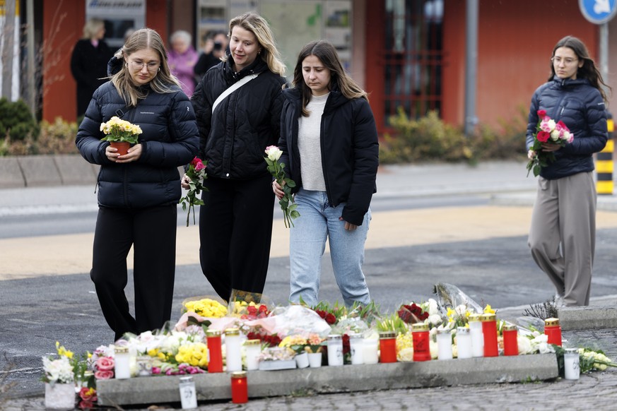 People lay flowers at the site where a postal bus caught fire in the center of Kerzers, Switzerland, Wednesday, March 11, 2026. According to the Fribourg cantonal police, six people died and five othe ...