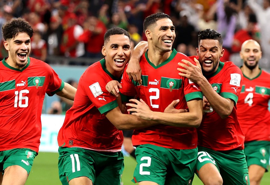 epa10352472 Players of Morocco celebrate with Achraf Hakimi (C) after he scored the last penalty kick which sent Morocco to the quarter final during the FIFA World Cup 2022 round of 16 soccer match be ...