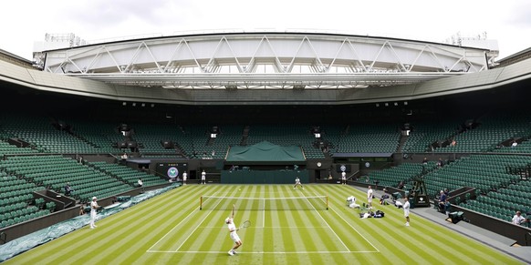 Italy&#039;s Jannik Sinner, bottom, and Serbia&#039;s Novak Djokovic practice at the All England Lawn Tennis and Croquet Club in Wimbledon, England ahead of the championships which start on Monday, Th ...
