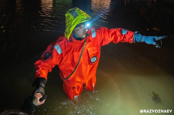 In this photo released by the Governor of Sevastopol, Mikhail Razvozhayev telegram channel, a rescuer gestures as he helps people during an evacuation after storm and flooding in Sevastopol, Crimea, M ...