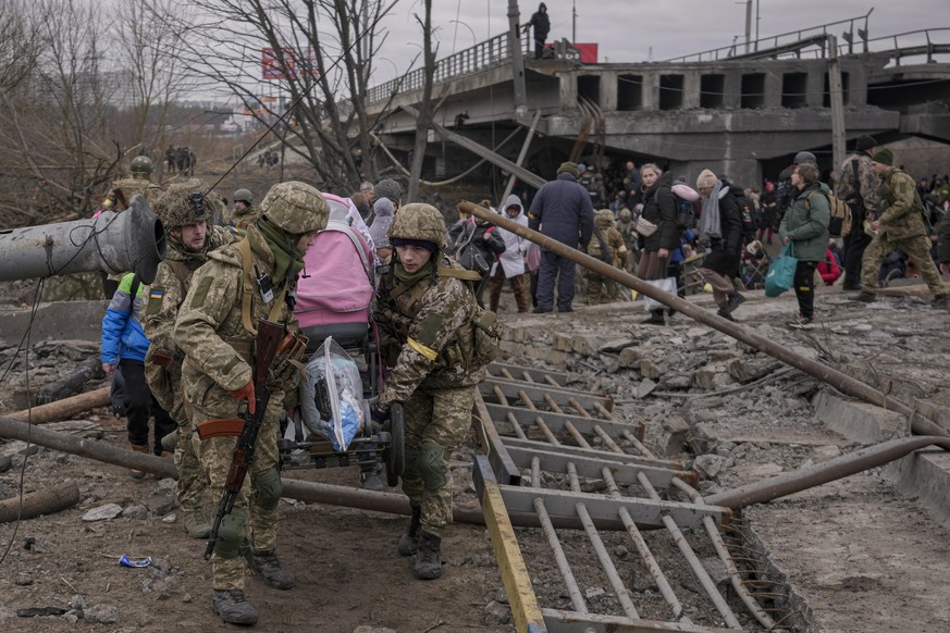 Ukrainian servicemen carry a baby stroller after crossing the Irpin river on an improvised path under a bridge, that was destroyed by Ukrainian troops designed to slow any Russian military advance, wh ...