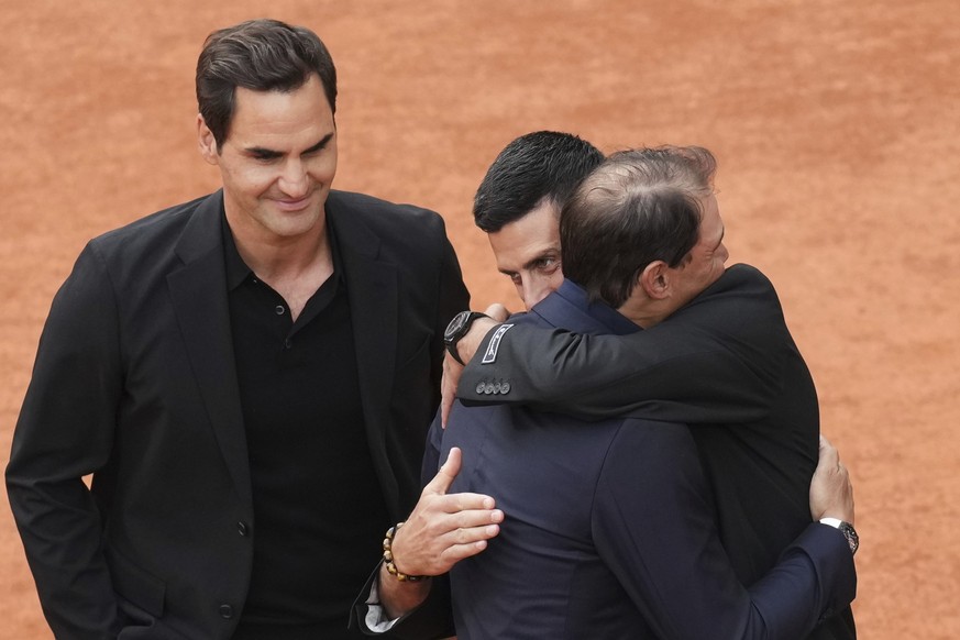 Rafa Nadal, second right, is hugged by Novak Djokovic as Roger Federer, left, look at them, during a farewell ceremony at center court Philippe-Chatrier, at the Roland-Garros stadium, in Paris, Sunday ...