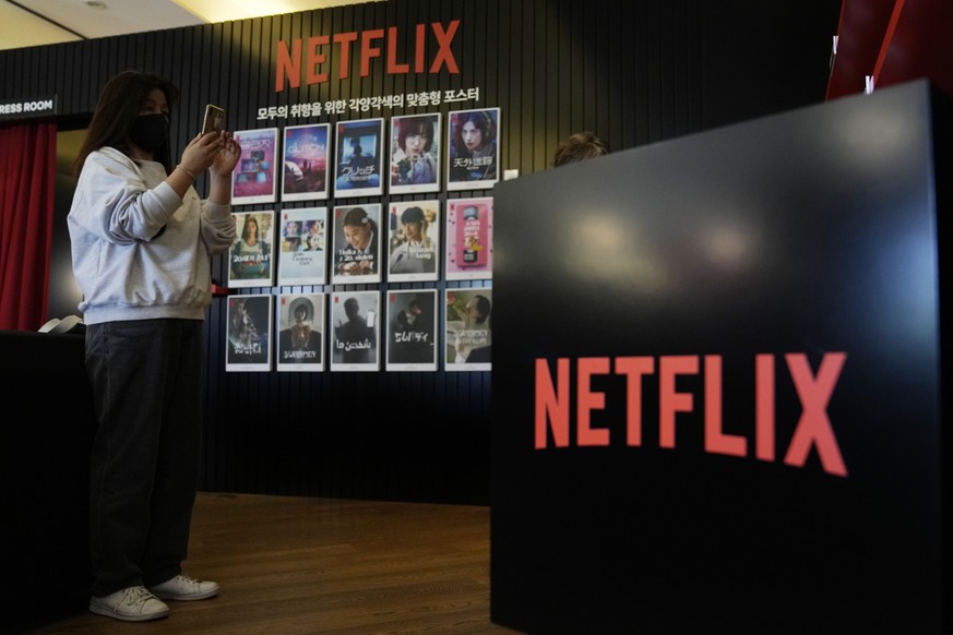 A visitor takes pictures beside 2022 Netflix Korea series and film posters during the 27th Busan International Film Festival (BIFF) in Busan, South Korea, Friday, Oct. 7, 2022. (AP Photo/Ahn Young-joo ...