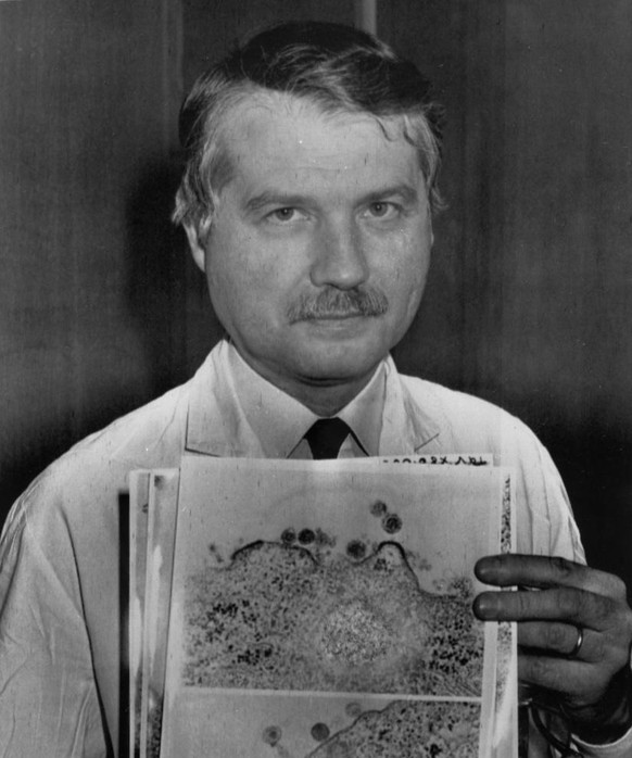 Dr. Luc Montagnier of the Pasteur Institute in Paris, France, holds two images April 24, 1984, in his office of two types of AIDS viruses. The top photo shows human T-cells leukemia virus (HTLV-Virus) ...