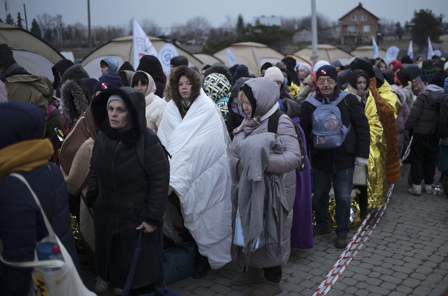 Refugees wait in a crowd for transportation after fleeing from the Ukraine and arriving at the border crossing in Medyka, Poland, Monday, March 7, 2022. Hundreds of thousands of Ukrainian civilians at ...