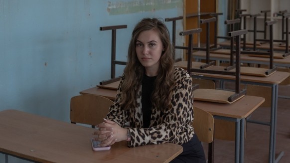 Violetta Dezhyna, 21, who works for the local administration poses for a portrait in the classroom she used to study in, at a school in the town of Izium, in the eastern Kharkiv region on July 29, 202 ...