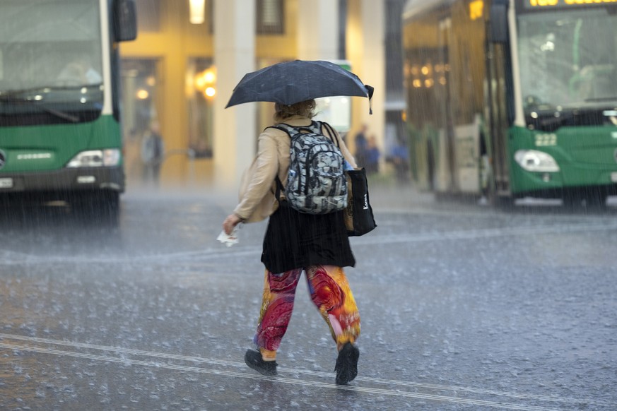 Une femme a l&#039;abri de son parapluie court sous une pluie battante sur la place de la gare lors d&#039;un episode orageux, ce mardi 30 aout 2022 a Morges. (KEYSTONE/Salvatore Di Nolfi)