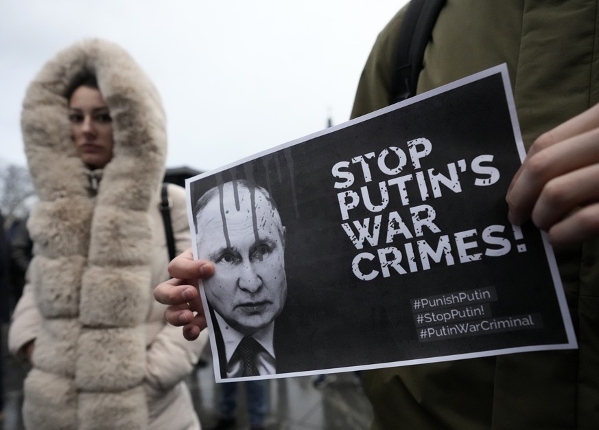 A man holds a banner showing a picture of Russian President Vladimir Putin during a protest against the Russian invasion and in solidarity with the Ukrainian people, in Belgrade, Serbia, Saturday, Dec ...