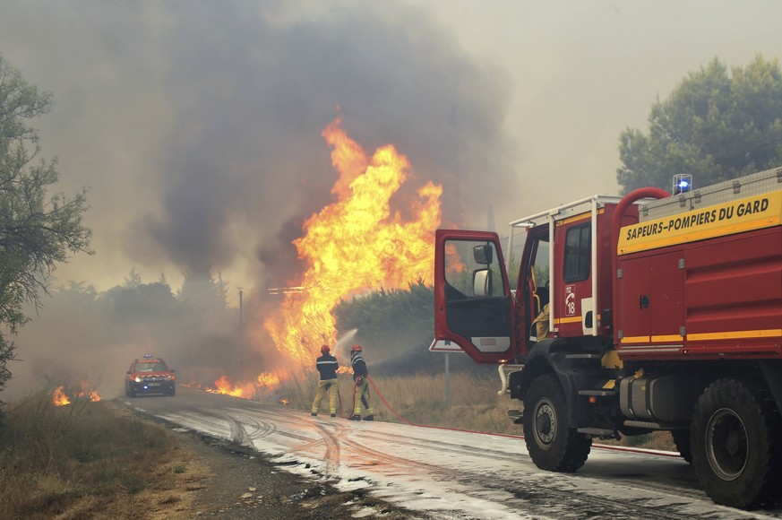 This photo provided by the fire brigade of the Gironde region (SDIS 30) shows shows firefighters put water on a trees at a forest fire in Aubais, southern France, July 31, 2022. A weekend wildfire in  ...