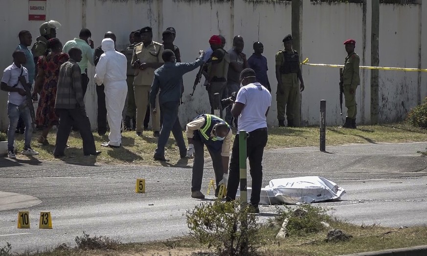 In this image made from video, security forces and forensic experts stand near a covered body in the street near the French embassy in Dar es Salaam, Tanzania Wednesday, Aug. 25, 2021. Tanzania&#039;s ...
