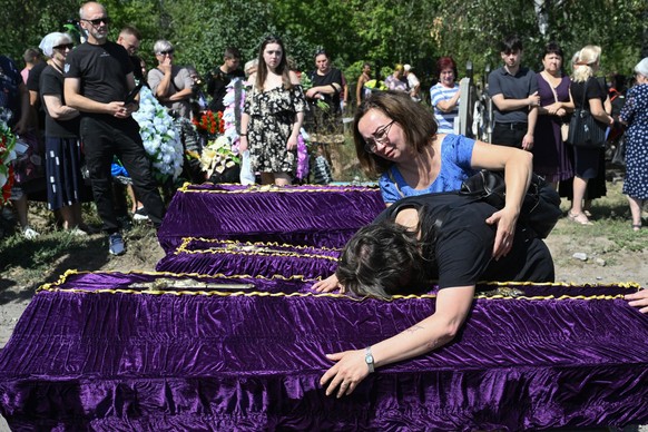 Relatives and friends mourn over coffins during a funeral ceremony for Mykyta and Sofia Lamekhov and their son Lev at a cemetery in Sloviansk, on August 5, 2025, amid the Russian invasion of Ukraine.
