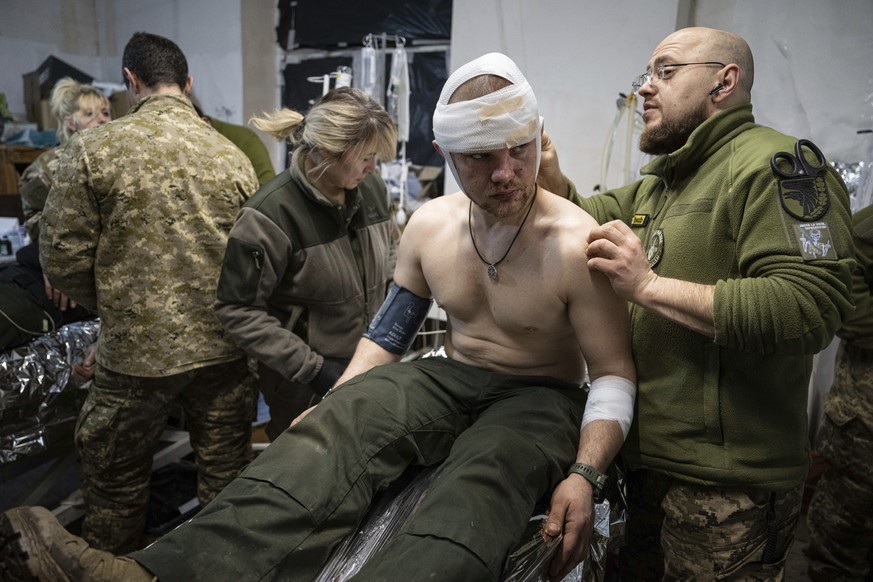 A Ukrainian military medic treats his wounded comrade at the field hospital near Bakhmut, Ukraine, Sunday, Feb. 26, 2023. (AP Photo/Evgeniy Maloletka)
