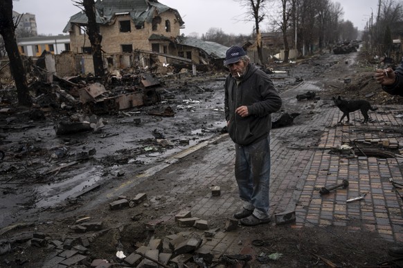 Konstyantyn, 70, smokes a cigarette amid destroyed Russian tanks in Bucha, in the outskirts of Kyiv, Ukraine, Sunday, April 3, 2022. (AP Photo/Rodrigo Abd)