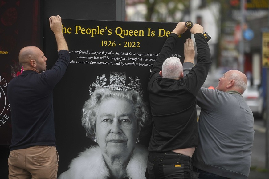 Council workers and local community representatives hang a mural on a wall on Crimea street off the Shankill road in Belfast following the death of Queen Elizabeth II, Friday Sept. 9, 2022. The countr ...