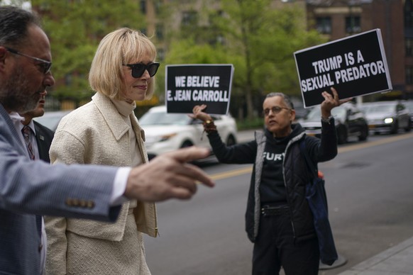 While a protester holds up signs, E. Jean Carroll arrives to federal court in New York, Thursday, April 27, 2023. Carroll began testifying Wednesday in the trial of her federal lawsuit. The writer has ...