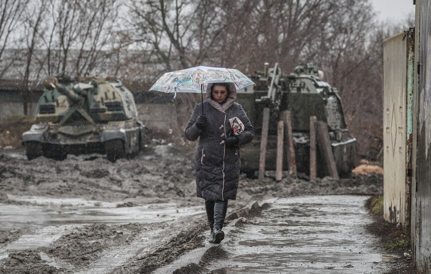 epa09780885 A woman walks in front of Russian armoured vehicles at the railway station in Rostov region, Russia, 24 February 2022. Russian troops launched a major military operation on Ukraine on 24 F ...