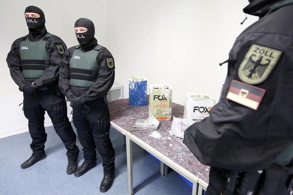 24.02.2021, Hamburg: Zollbeamte stehen an einem Tisch im Zollfahndungsamt Hamburg, auf dem Kokain liegt. In f�nf Containern aus Paraguay hat der Hamburger Zoll mehr als 16 Tonnen Kokain sichergestellt ...