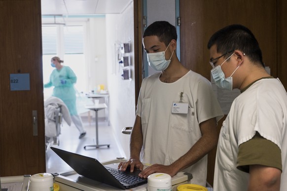 Die Soldaten Liu Kelun, rechts, und Andreas von Bueren erfassen Daten eines Covid-19 Patienten, die ihnen die Pflegefachfrau durchgibt, im Freiburger Spital (HFR), am Mittwoch, 8. April 2020 in Freibu ...