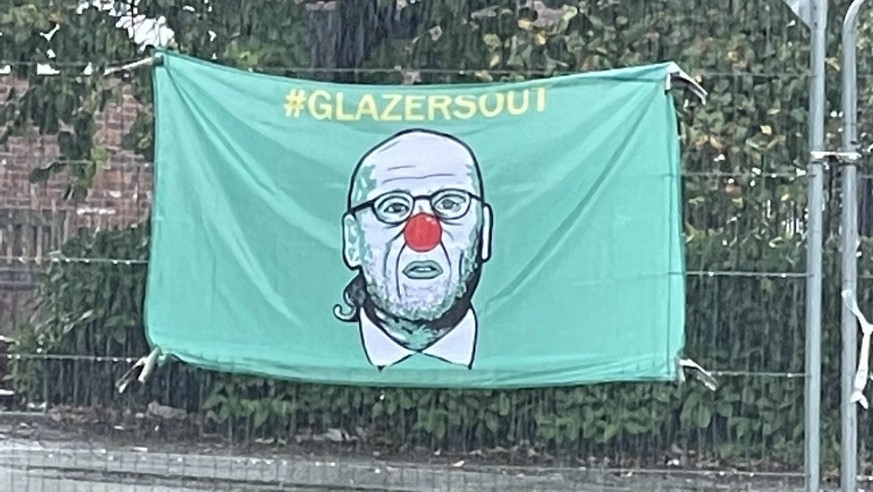 Une banderole accrochée à un grillage près du stade de Manchester United, représentant le propriétaire des Red Devils, Joël Glazer, avec un nez rouge.