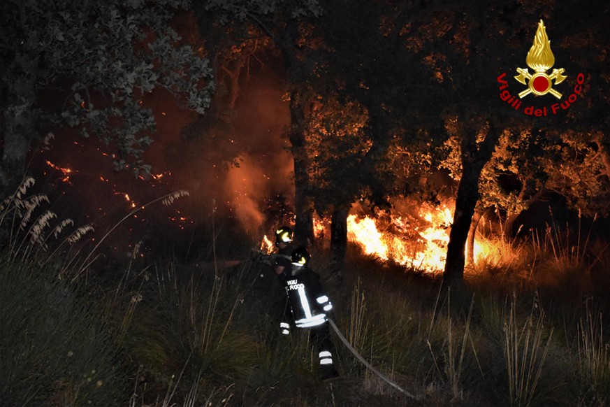 epa09379687 A handout photo made available by Vigili del Fuoco (VVF), the Italian National Fire Brigade, shows VVF members conducting extinguishing operations of a forest fire affecting an area betwee ...