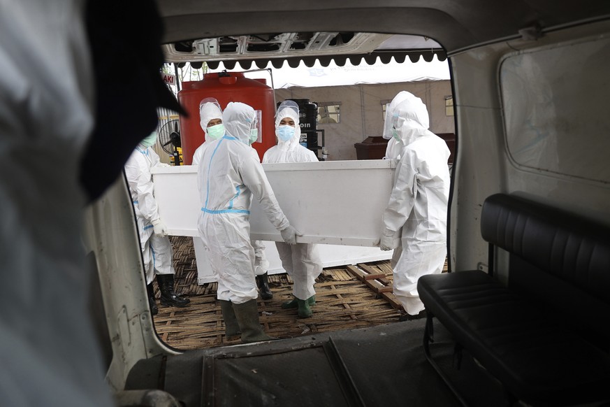 FILE - Health workers carry a coffin containing the body of a COVID-19 victim into an ambulance for burial in Surabaya, East Java, Indonesia, July 10, 2021. The global death toll from COVID-19 has top ...