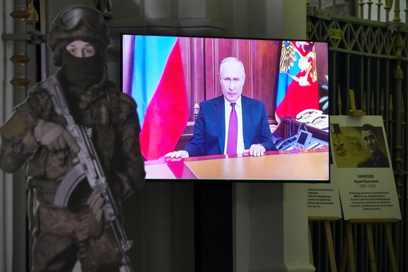 A TV screen shows Russian President Vladimir Putin announcing the beginning of the military operation in February 2022, next to a cardboard cutout depicting a Russian soldier, at an exhibition dedicat ...