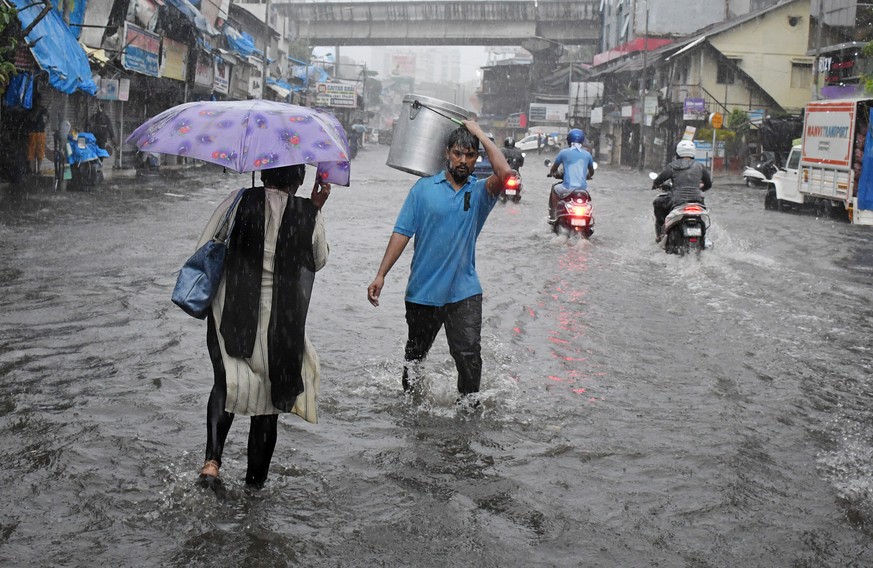 epaselect epa09207145 Indian people wade through flooded street during heavy rainfall after cyclone Tauktae hits Mumbai and nearby areas, India, 17 May 2021. According to the India Meteorological Depa ...