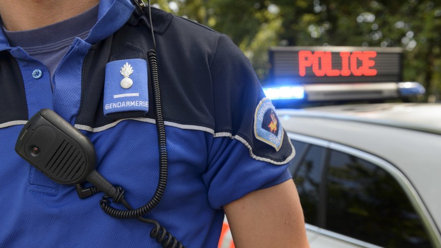 Un policier de la Police cantonale genevoise pose a cote d&#039;un panneau indiquant police sur une voiture, pour des photos d&#039;illustration, ce vendredi 31 juillet 2015 a Geneve. (KEYSTONE/Martia ...