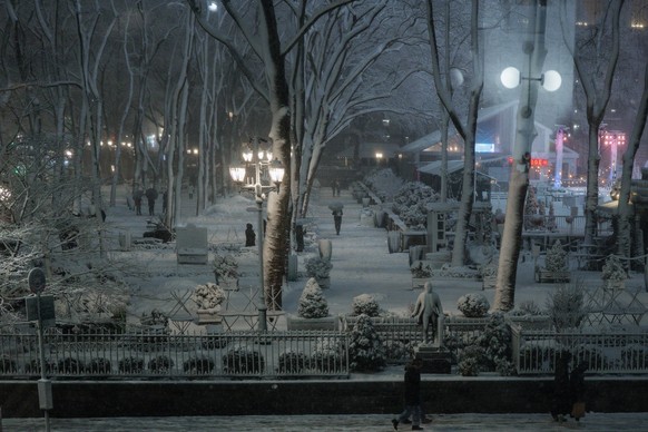 epa12770731 People walk in Bryant Park during the winter blizzard in New York, New York, USA, 22 February 2026. The National Weather Service has issued a blizzard warning for New York City, forecastin ...
