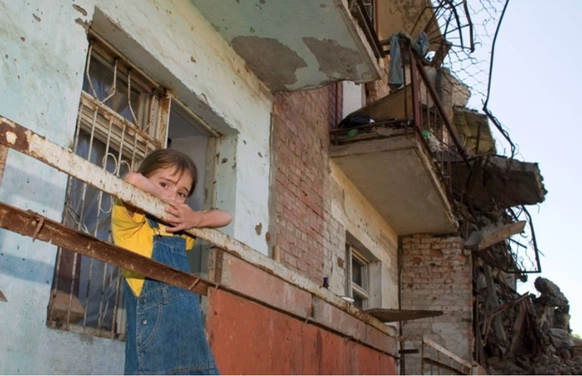 Une jeune fille regarde par-dessus le balcon d'un immeuble d'habitation détruit à Grozny, la capitale de la Tchétchénie.