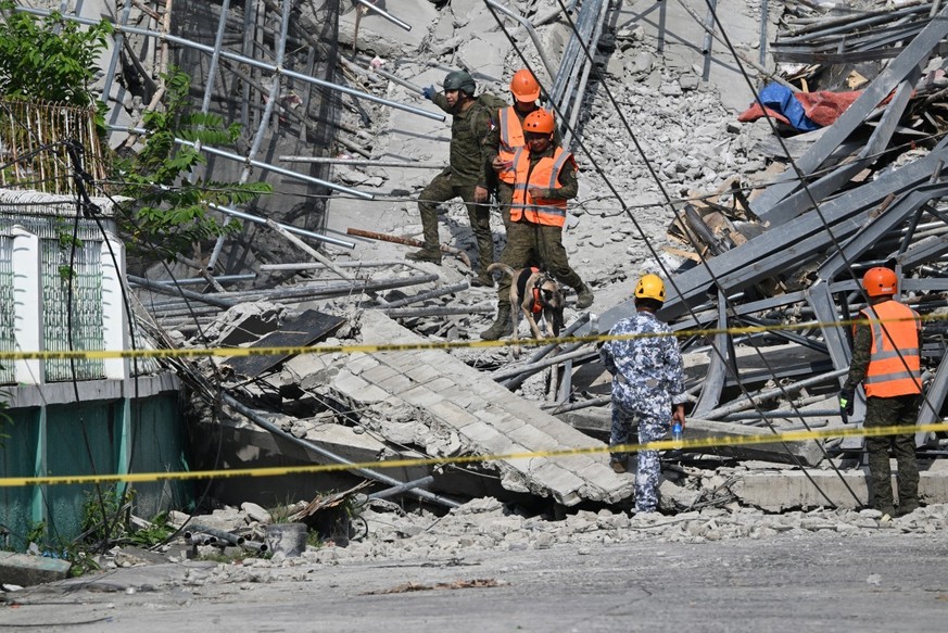 Military personnel with a working dog conduct search and rescue operations at a collapsed building in Angeles City, Pampanga province, north of Manila on May 25, 2026. The death toll rose to three on  ...