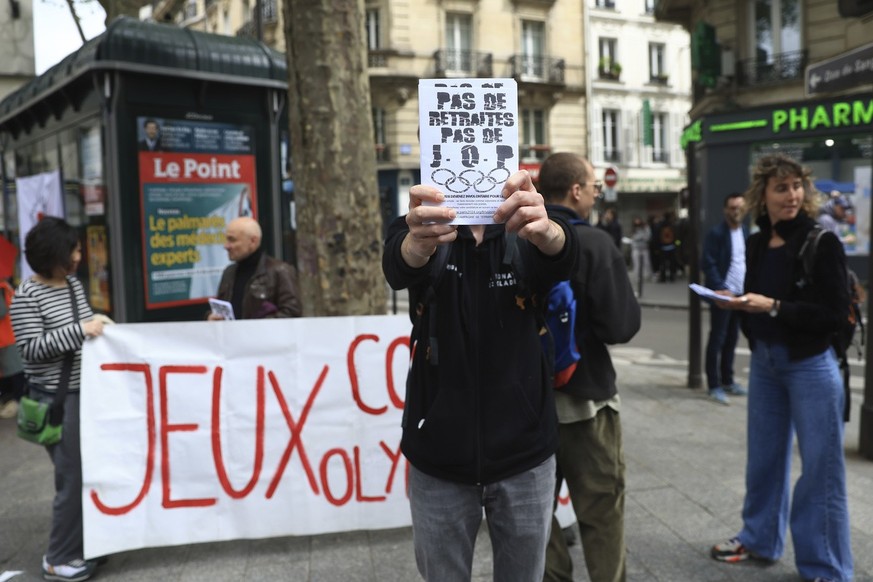 Activists stage a protest against Paris 2024 Olympics, one showing a leaflet reading &quot;No withdrawal of the pension reform, no Olympic Games&quot;, in Paris, Monday, May 1, 2023. Olympic contestat ...